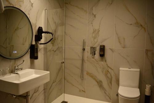 a bathroom with a sink and a shower with a mirror at Corona de Galicia Rooms in Padrón