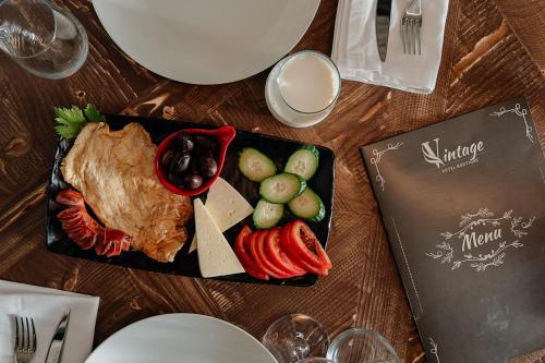 een bord met eten met vlees en groenten op een tafel bij Vintage Boutique Hotel in Korçë