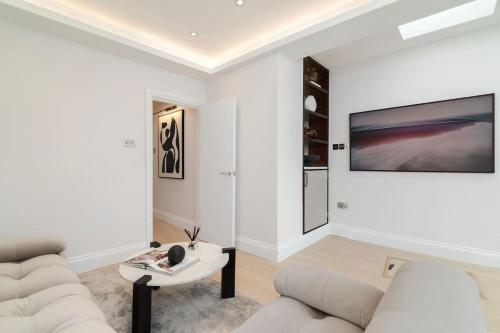 a white living room with a couch and a table at Newly refurbished cosy 2 bed in Wembley in London