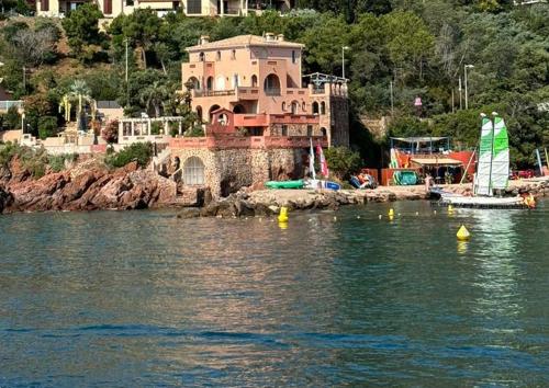 une maison sur la rive d'une étendue d'eau avec des bateaux dans l'établissement Villa de prestige en bord de mer dans la baie de Cannes, à Théoule-sur-Mer