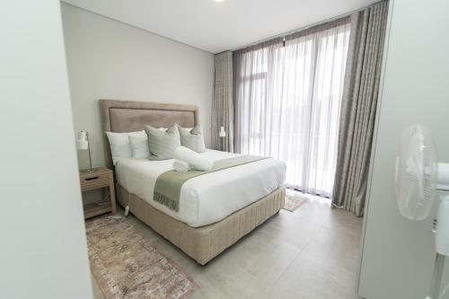 a bedroom with a large bed and a large window at Summerstrand Escape Bella Mare in Gqeberha