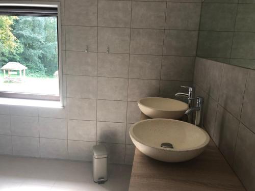 une salle de bain avec deux lavabos et une fenêtre dans l'établissement Charmant logement, à Saint-Amand-de-Vergt