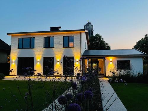 a large white house with lights in the yard at Villa Couleur in Diksmuide