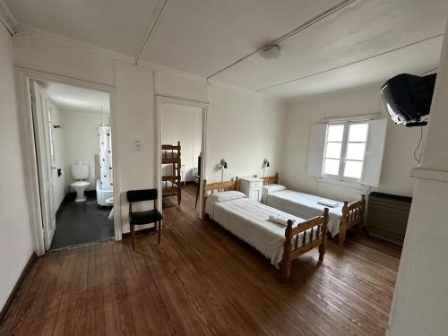 a large room with two beds and a chair at Hotel Paris in Río Gallegos