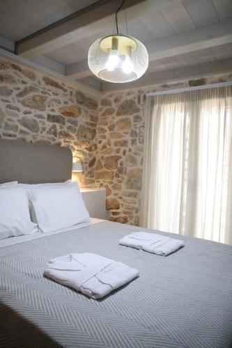 a bedroom with a bed with towels on it at Kapetanospito Vacation Homes in Kardámyla