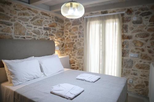 a bedroom with a bed with two towels on it at Kapetanospito Vacation Homes in Kardámyla
