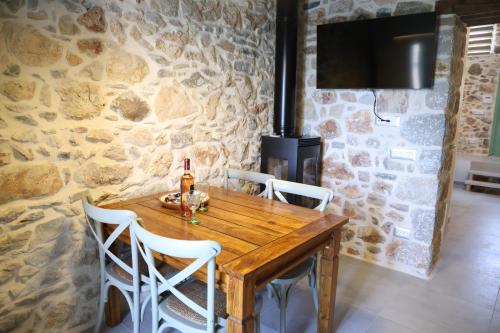 a dining room with a wooden table and a stone wall at Kapetanospito Vacation Homes in Kardámyla