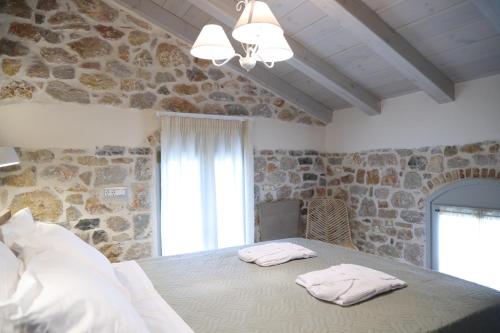 a bedroom with a bed with two towels on it at Kapetanospito Vacation Homes in Kardámyla
