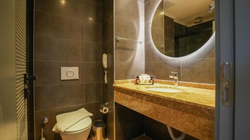 a bathroom with a sink and a toilet and a mirror at Ada Port Hotel Adults Only in Alanya
