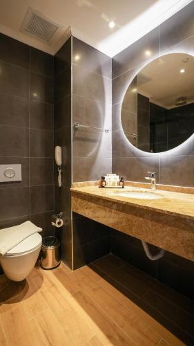 a bathroom with a toilet and a sink and a mirror at Ada Port Hotel Adults Only in Alanya