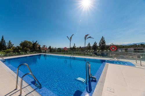 a large swimming pool with blue water at NEW Elegant 3BR Townhouse in Chaparral Golf & Spa & Gym in Mijas Costa