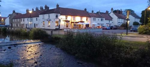 a hotel with a river in front of a building at The Buck Hotel in Great Ayton