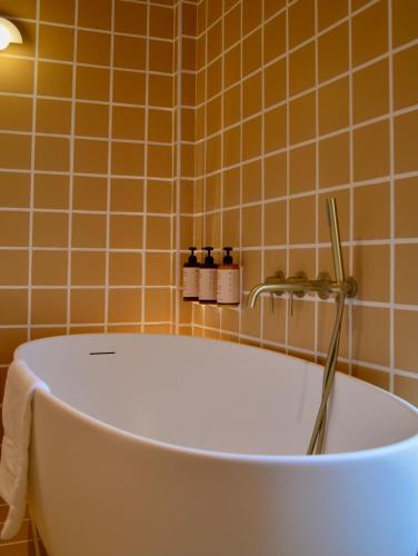a bath tub in a bathroom with orange tiles at Hotel M Soleil - Montpellier Centre Saint Roch in Montpellier