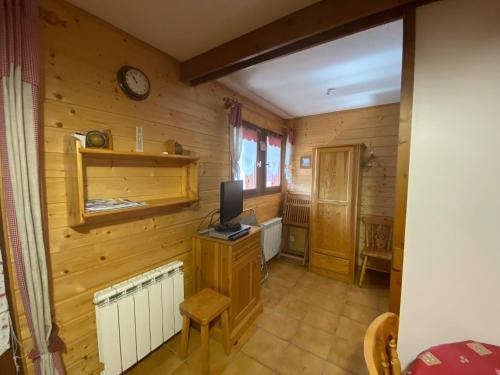 Cette chambre est dotée de murs en bois et d'une télévision sur un bureau. dans l'établissement Appartement avec balcon à Praz-sur-Arly 40 m² vue montagne, à Praz-sur-Arly
