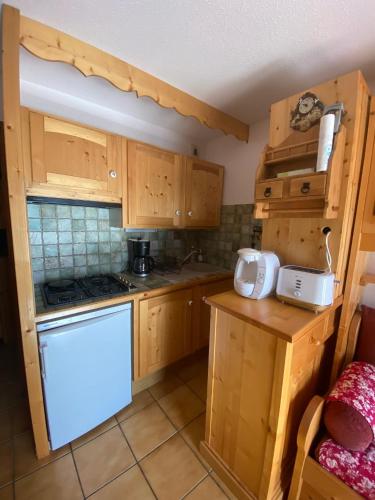 une cuisine avec des armoires en bois et un four à plaques de cuisson dans l'établissement Appartement avec balcon à Praz-sur-Arly 40 m² vue montagne, à Praz-sur-Arly