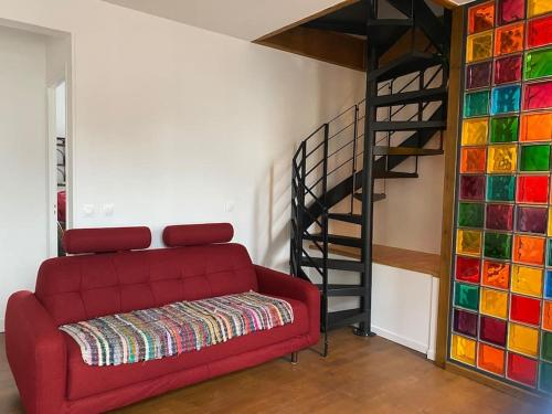 - un salon avec un canapé rouge et un escalier en colimaçon dans l'établissement Maison du Cap Lihou, Duplex au 1er et 2ème étage mansardé, Quartier Historique, GRANVILLE, à Granville