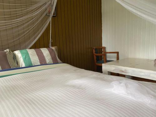 a bed in a room with a table and a chair at My Lily Cottage Naivasha in Naivasha