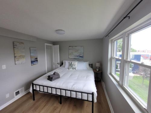 a bedroom with a bed with white sheets and a window at Davenport Dwellings 2 Bd by UNMC in Omaha
