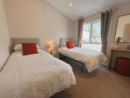 a bedroom with two beds and a window at 2 Lakeside, Luxury lodge with private garden & parking in Patrington