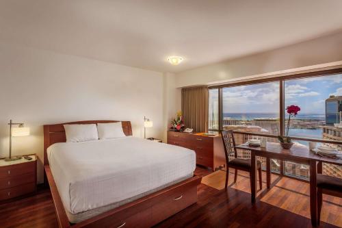 a bedroom with a bed and a desk and a table with a desk at Aston at the Executive Centre Hotel in Honolulu
