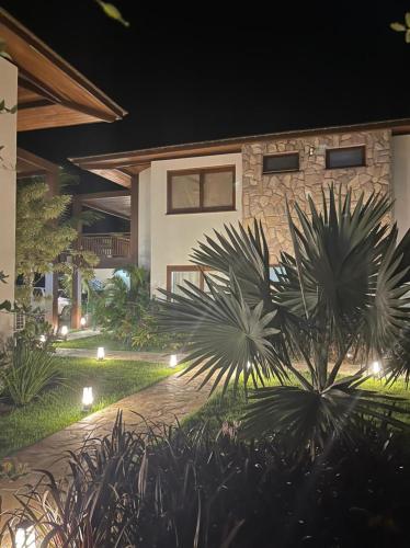 a house with lights in a garden at night at Villagio Di Mare in Marau