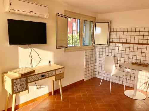een kamer met een bureau en een tv aan de muur bij Dimora Zizzi in Fasano