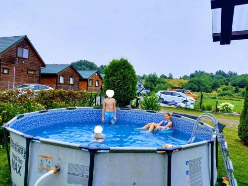un uomo e due bambini in una piscina di Domki letniskowe Reda a Rusinowo