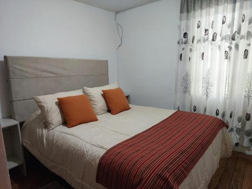 a bed with two orange pillows in a bedroom at Pawllu Inqa Lodge in Cusco
