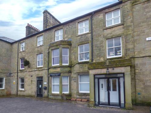 un vecchio edificio in mattoni con un garage di fronte di 12 Eagle Parade a Buxton