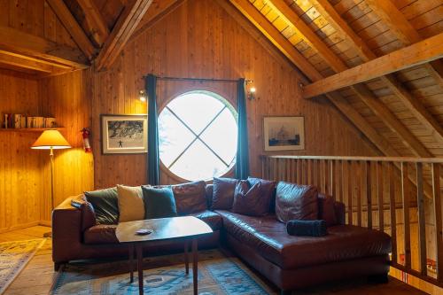 a living room with a leather couch and a window at Refuge Exitchalets Spa & View in Sainte-Lucie-de-Doncaster