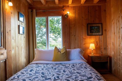 a bed in a wooden room with a window at Refuge Exitchalets Spa & View in Sainte-Lucie-de-Doncaster