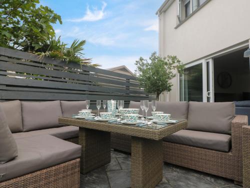 a patio with a table and couches on a balcony at Pickney House in Looe