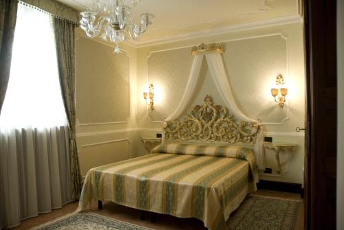Appartamento Ca' Cavalli في البندقية: غرفة نوم بسرير مع مظلة وثريا