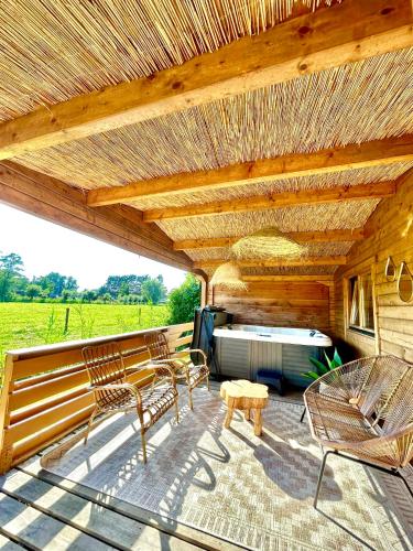 a patio with chairs and a table and a wooden roof at Mediterranean style chalet with jacuzzi and garden near Amsterdam in Vijfhuizen