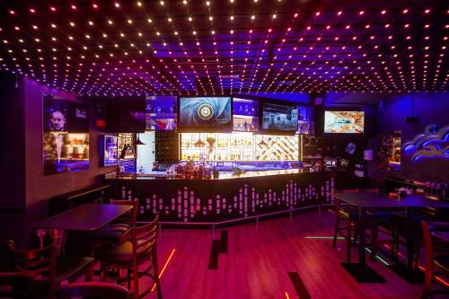 a bar with purple lighting and tables and televisions at Grand Villaggio Hotel Abu Dhabi in Abu Dhabi