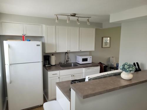 a kitchen with white cabinets and a white refrigerator at Davenport Dwellings 10- By UNMC in Omaha