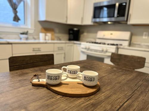 three coffee mugs on a wooden tray on a kitchen table at Chic City Escape in Berwyn
