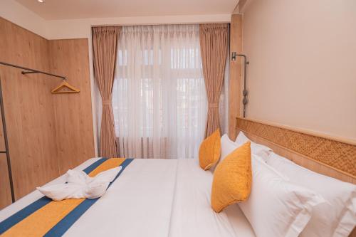 a bed with yellow and white pillows and a window at Hotel Vistara in Kathmandu