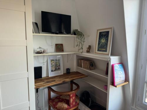 une pièce avec une étagère avec une télévision et un bureau dans l'établissement Charmant Studio 5min de Paris, à Levallois-Perret
