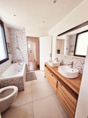 une salle de bain avec deux lavabos et une baignoire et des toilettes dans l'établissement belle Maison familiale, jardin, à LʼÎle-Saint-Denis