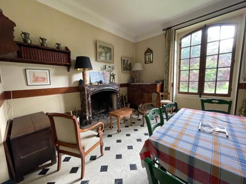une pièce avec une table, des chaises et une cheminée dans l'établissement Au bout des platanes, à Méhers