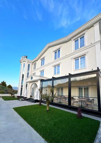 a large white building with a lawn in front of it at Reign Hotel in Vorë