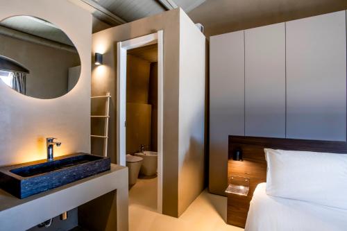 a bathroom with a bed and a sink and a mirror at Villa Petra Noto - Rooms and More in Noto