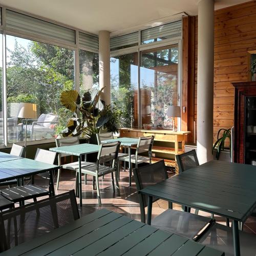 una sala da pranzo con tavoli, sedie e finestre di La Maison Du Coteau a Cachan