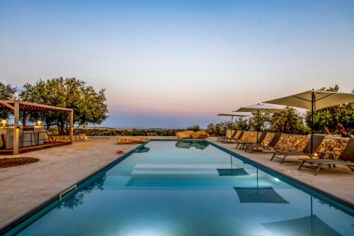 a pool with chairs and umbrellas at a resort at Villa Petra Noto - Rooms and More in Noto