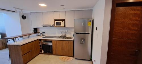 Una cocina con refrigerador de acero inoxidable y gabinetes de madera. en Loft Granda Centeno, en Quito