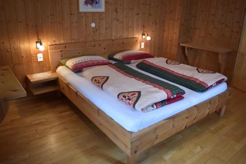 a bed in a wooden room with two pillows on it at Ferienwohnungen Bulandhof in Valdaora