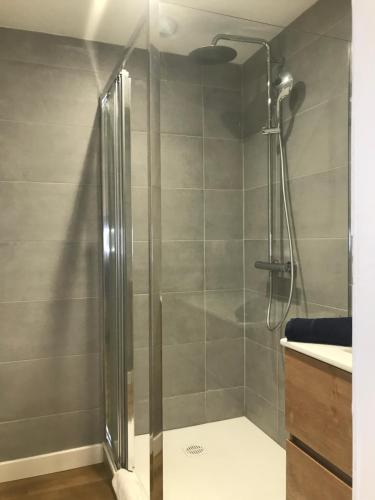 une douche avec une porte vitrée dans une salle de bain dans l'établissement LE LARBAUD - Hypercentre - Clim - Thermes- RDC, à Vichy