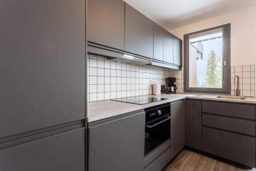 d'une cuisine équipée d'appareils en acier inoxydable et d'une fenêtre. dans l'établissement Résidence Les Brigues - maeva Home - Appartement 2 Pièces 6 Personnes - Sélection MAE-4708, à Courchevel