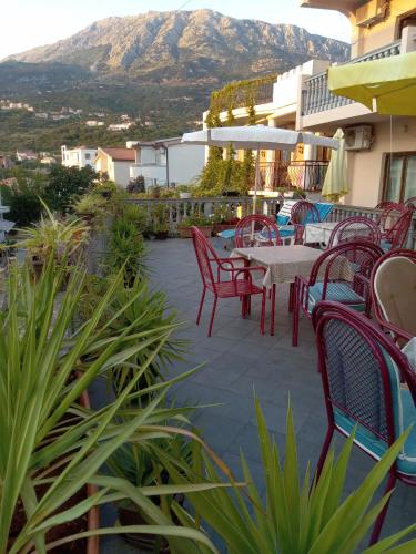 a patio with red chairs and a table with a mountain at Tanja Terrace Appartments Dobre Vode in Dobra Voda